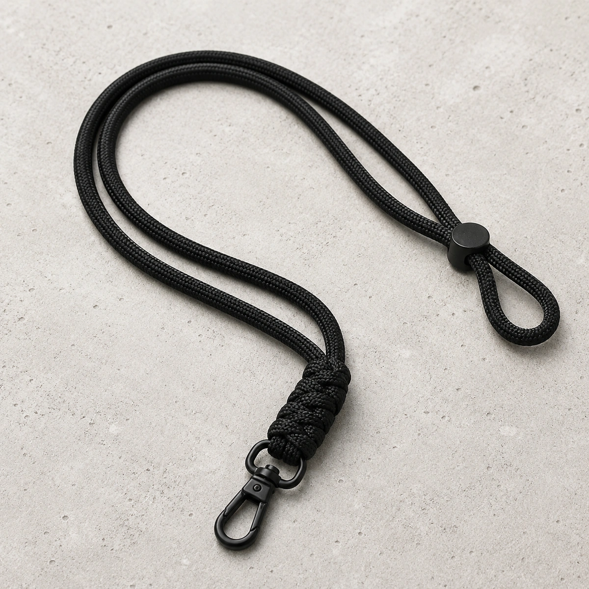 zwart crossbody telefoonkoord met telefoonpatch op lichte betonnen achtergrond