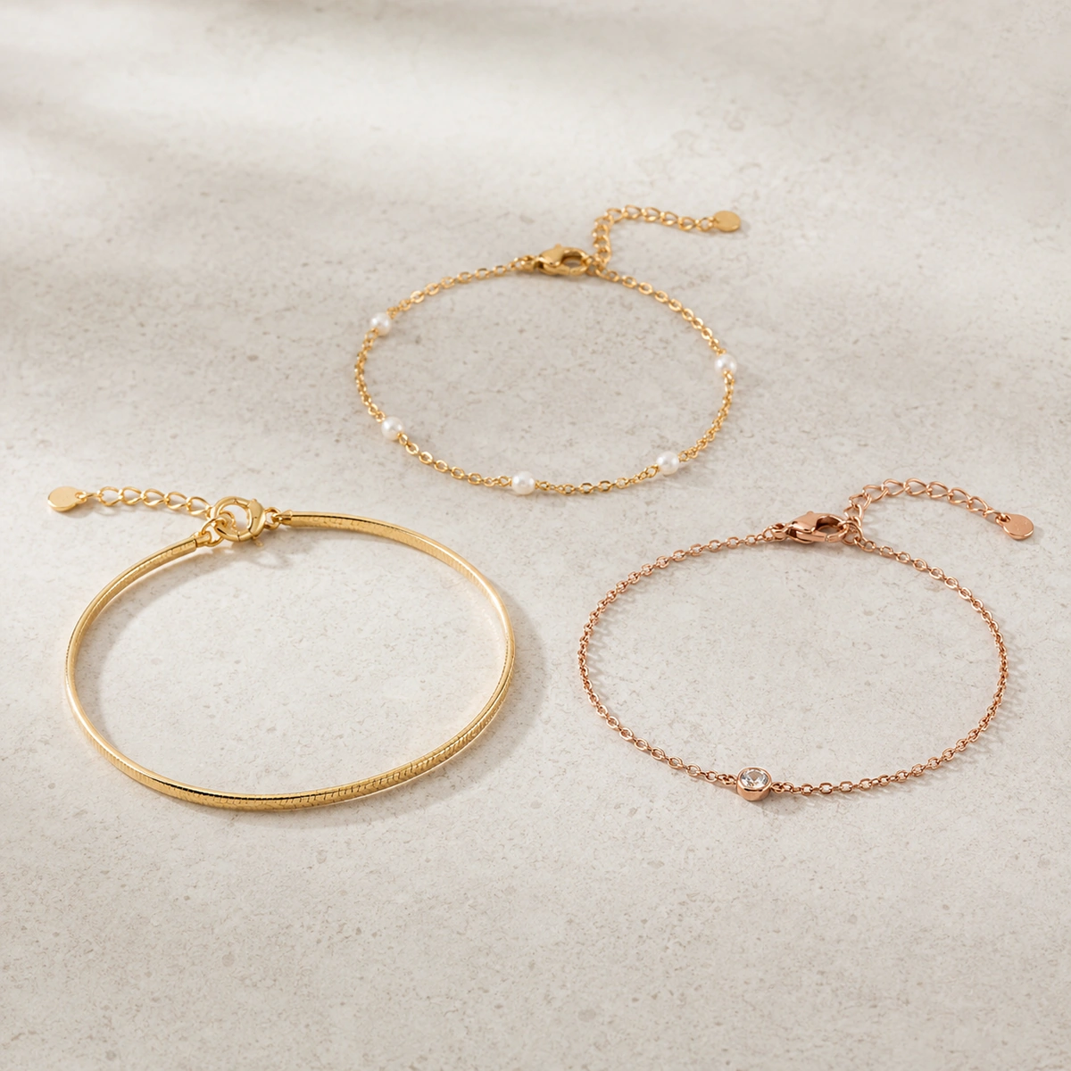 minimalistische armbanden set met fijne schakelarmband en smalle bangle op lichte betonnen achtergrond