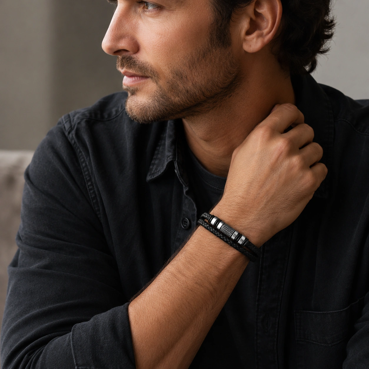 man met zwarte leren armband en stalen details bij een rustige casual outfit