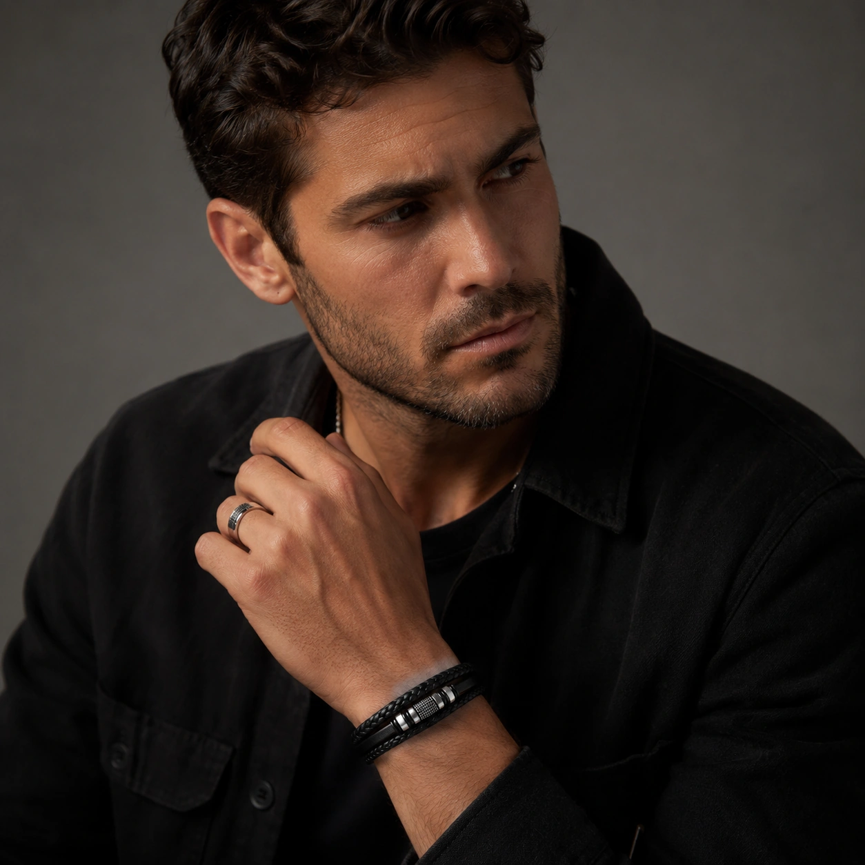 man draagt leren armband met stalen ring en donkere casual kleding