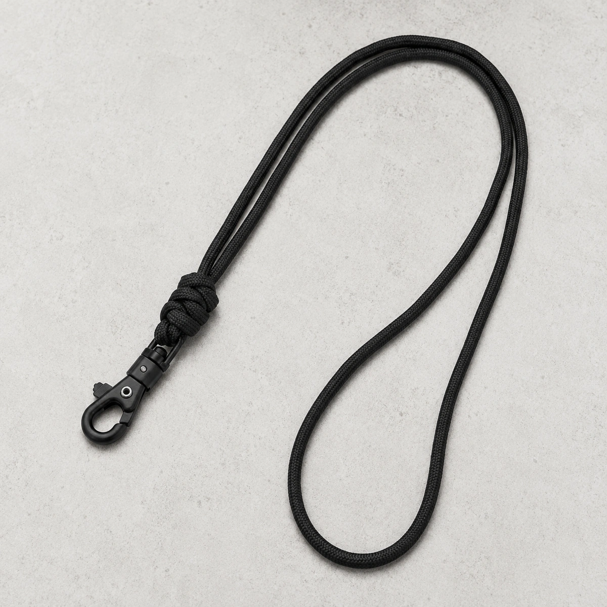 zwart paracord telefoonkoord met karabijnsluiting op lichte betonnen achtergrond
