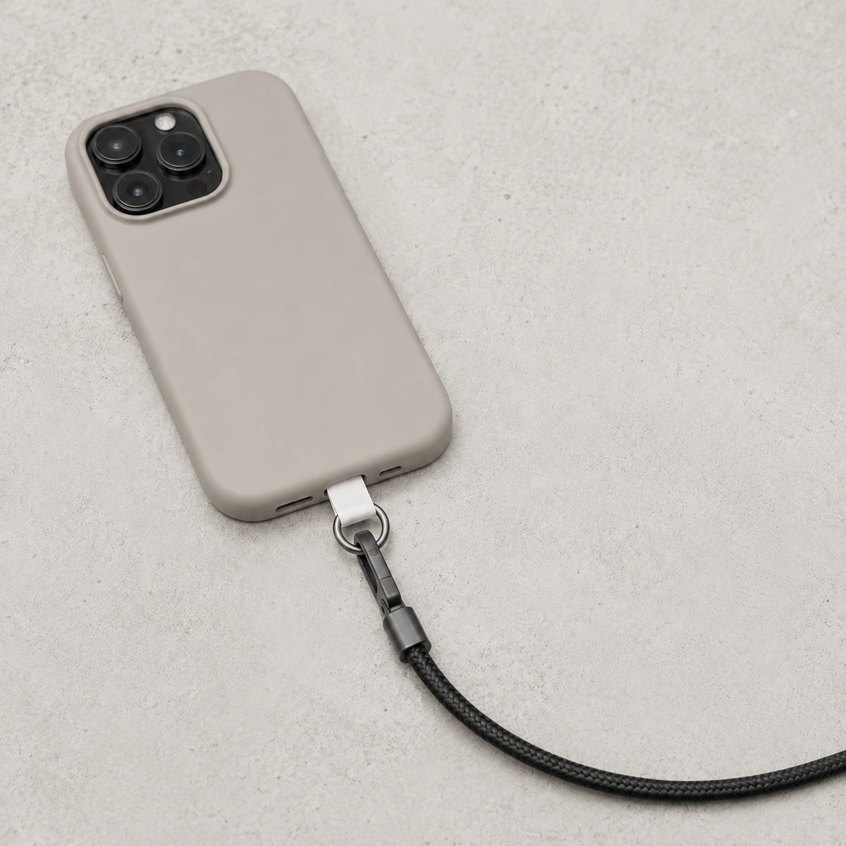 telefoonpatch met zwart telefoonkoord en neutraal telefoonhoesje op lichte betonnen achtergrond
