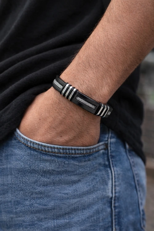 Model draagt Rubberen Armband Heren met siliconen band, RVS mesh en zilverkleurige details in zwart